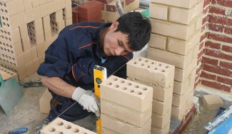 Person measuring stacked bricks