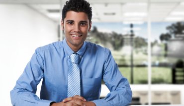 Smiling man wearing tie, sitting at desk