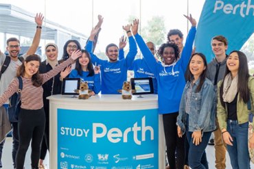 Group of 12 student volunteers smiling at the Perth Airport Welcome Desk